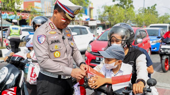 Dirlantas Polda Kaltara memasang bendera merah putih di kendaraan pengendara roda dua.