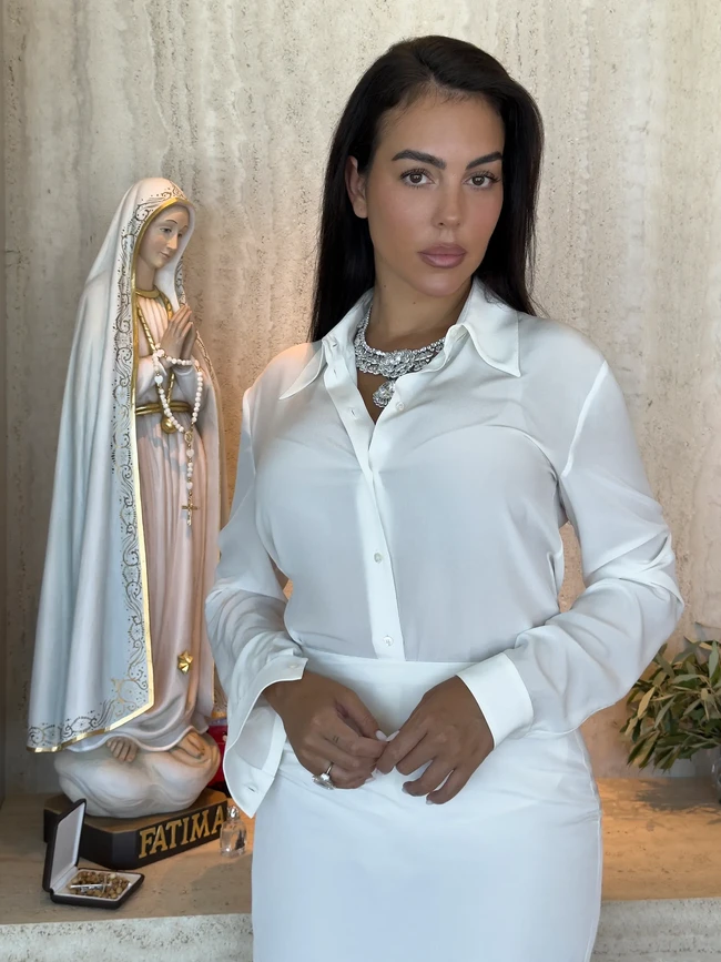 Kesederhanaan juga terlihat dari pilihan busana pengantin. Alih-alih gaun putih panjang,  Georgina memilih busana yang lebih minimalis. Model sekaligus ibu lima anak itu mengenakan white silk faille skirt suit, berupa setelan putih dengan rok berbahan silk faille. (Foto: Vogue/Juergen Teller)