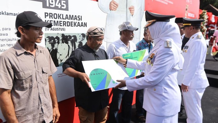 Bupati Ipuk Fiestiandani menyerahkan secara simbolis kartu kepesertaan BPJS Ketenagakerjaan kepada beberapa pekerja rentan di Banyuwangi.