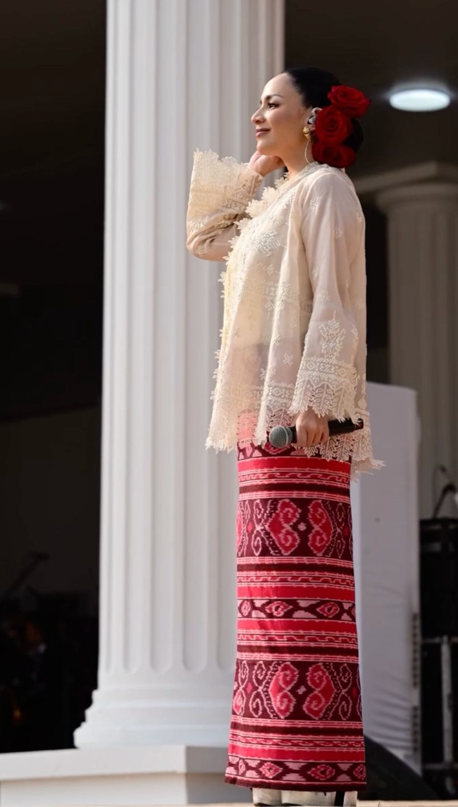 Angel Pieters tampil anggun saat menyanyikan Zamrud Khatulistiwa di Upacara HUT ke-81 RI di Istana Negara. Angel mengenakan outer rancangan Biyan dan kain bermotif etnik dominasi merah. Penampilannya semakin mencuri perhatian dengan detail aksesori mawar merah yang disematkan pada sanggulnya. Foto: Dok. Instagram hummingbirdroad, hagaipakan, cita rahayu, marcel siahaans, angel pieters