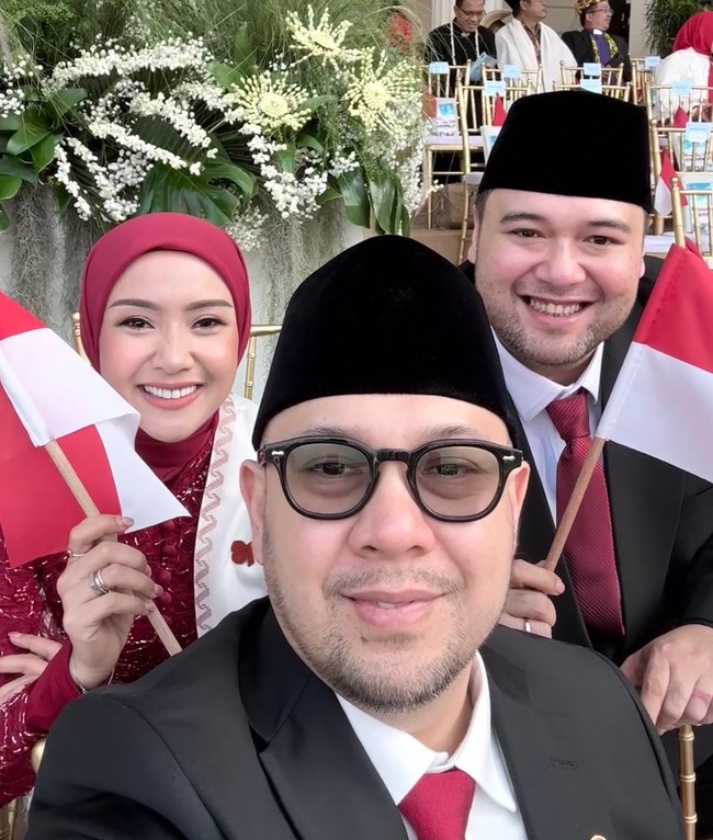 Gaya hijab merah polos dengan model clean look membingkai riasan wajah Cita yang flawless. Kebaya brokat berkerah tinggi yang dikenakannya makin serasi saat disandingkan dengan selendang putih dan bendera kecil yang dipegangnya. Foto: Dok. Instagram @cita_rahayu.