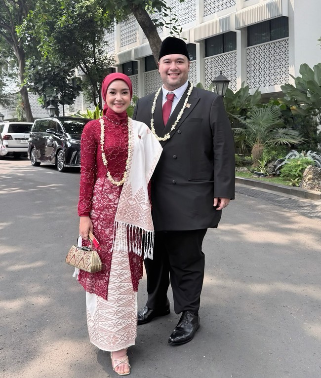 Tampilan full body memperlihatkan padu padan antara atasan kebaya brokat merah marun dan bawahan kain songket atau tenun bernuansa putih-krem. Lengkap dengan tas genggam etnik serta alas kaki yang simpel, penampilannya bersama Didik Mahardika terlihat serasi dan bernuansa formal. Foto: Dok. Instagram @cita_rahayu.
