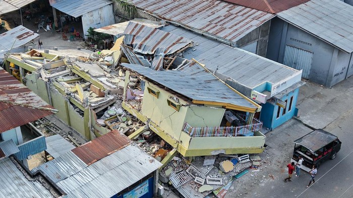 Warga melintas di dekat bangunan toko yang rusak akibat gempa di kawasan Reo, Kabupaten Manggarai, NTT, Senin (17/8/2026). Wilayah yang tersebut menjadi salah satu titik di Kabupaten Manggarai yang paling terdampak gempa bumi bermagnitudo 7,7 di NTT.