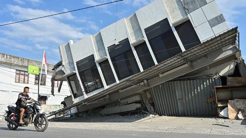 Warga melintas di dekat bangunan toko yang rusak akibat gempa di kawasan Reo, Kabupaten Manggarai, NTT, Senin (17/8/2026). Wilayah yang tersebut menjadi salah satu titik di Kabupaten Manggarai yang paling terdampak gempa bumi bermagnitudo 7,7 di NTT. ANTARA FOTO/Fikri Yusuf/foc.