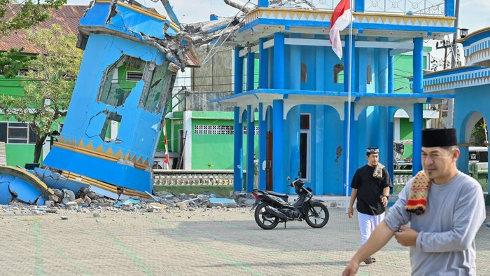Warga melintas di dekat bangunan toko yang rusak akibat gempa di kawasan Reo, Kabupaten Manggarai, NTT, Senin (17/8/2026). Wilayah yang tersebut menjadi salah satu titik di Kabupaten Manggarai yang paling terdampak gempa bumi bermagnitudo 7,7 di NTT. ANTARA FOTO/Fikri Yusuf/foc.