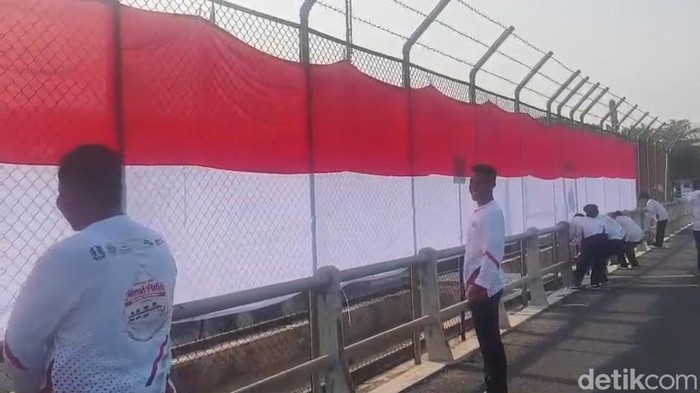 Puluhan pemuda membentangkan bendera Merah Putih sepanjang 180 meter di atas Bendung Gerak Babat, Kecamatan Laren, Lamongan, saat peringatan HUT ke-81 Kemerdekaan RI, Senin (17/8/2026). Aksi tersebut menjadi simbol kecintaan warga terhadap Indonesia.
