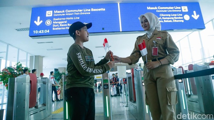 Petugas KAI menggunakan kostum pejuang kemerdekaan RI sambil membagikan bendera Merah Putih kepada penumpang di Stasiun BNI City, Jakarta, Senin (17/8/2026).