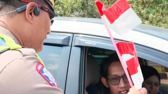 Petugas PJR Jatim 3 Polda Jatim bagi-bagi bendera usai upacara di tol.