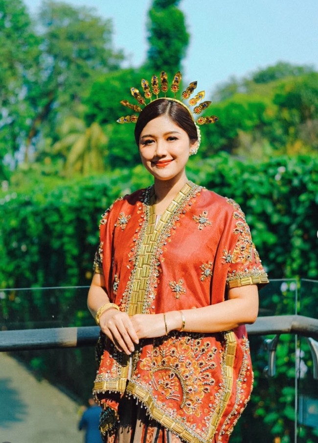 Erina mengenakan baju bodo modifikasi berpotongan longgar. Bagian depan dan tepi busana dihiasi bordiran emas yang mewah. Bagian permukaan baju ditaburi payet dan kristal. Ia juga melengkapi penampilannya dengan mahkota atau kembang goyang emas khas pakaian adat Sulawesi Selatan. Foto: Instagram/@erinagudono