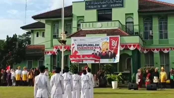 Foto: Petugas keamanan (satpam) sebuah kampus di Medan memanjat tiang bendera. (Tangkapan layar media sosial)