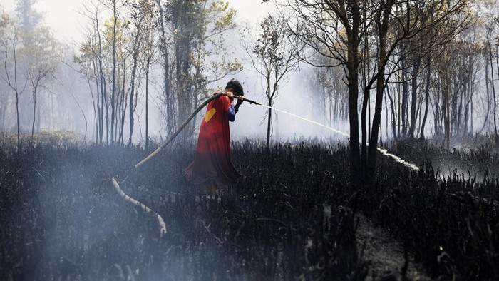 Rudiyansah, 16, wears a Superman costume while extinguishing a fire at a wildfire-affected area in Palangka Raya, Central Kalimantan province, Indonesia, August 14, 2026. REUTERS/Ajeng Dinar Ulfiana     TPX IMAGES OF THE DAY