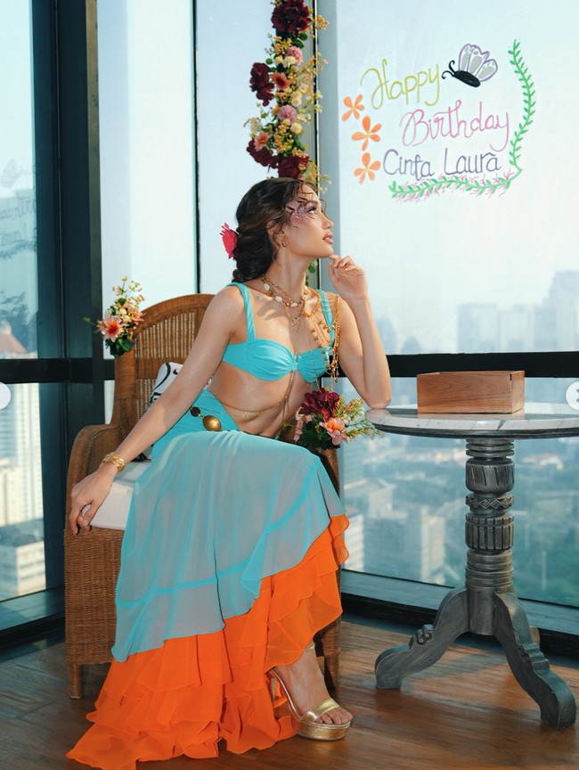Cinta tampil dengan setelan two-piece berupa atasan bra top dan rok tile yang sedikit menerawang. Ia memadukan penampilannya itu dengan sepasang heels warna emas dan perhiasan seperti anting, kalung beberapa layer, serta gelang. Foto: Instagram/@claurakiehl
