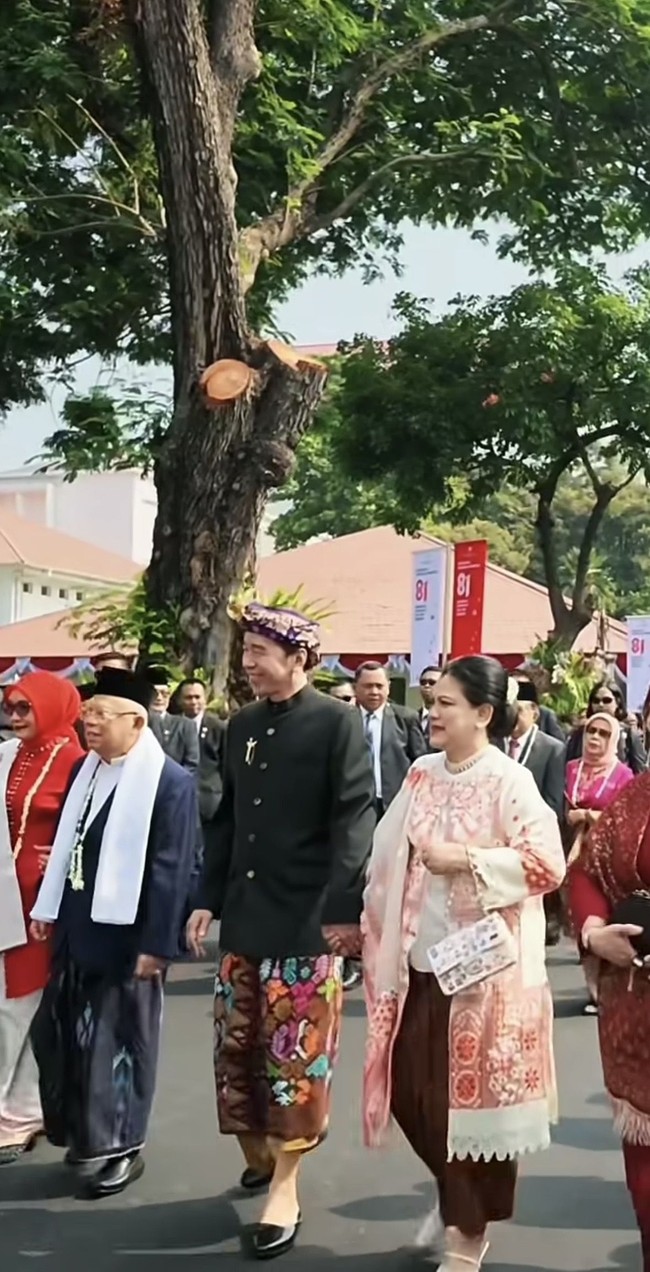 Penampilannya semakin lengkap dengan selendang panjang yang memiliki motif senada. Rambut Iriana ditata sederhana dengan gaya disanggul rapi sehingga memberikan kesan klasik dan elegan. Untuk alas kaki, ia memilih sepatu berwarna putih dengan detail tali tipis yang terlihat feminin. Foto: Instagram/@jokowi