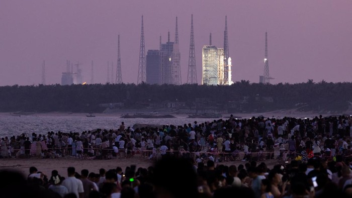 People gather at dusk at Qishui Bay Beach to watch the launch of a Long March 7A launch vehicle from the Wenchang Space Launch Site in Wenchang, Hainan province, China, August 10, 2026. On a sweltering August night, thousands on China's Hainan island thronged the beaches around the Wenchang Space Launch Site, phones raised, waiting for a show. Shortly after 8 p.m., the Long March 7A rocket blasted off. The crowd roared as its ascent lit up the night sky. Moments later, the uncrewed rocket turned into a ball of fire in midair, an unforeseen blast confirmed by Chinese state media a few hours afterwards. REUTERS/Maxim Shemetov            SEARCH 