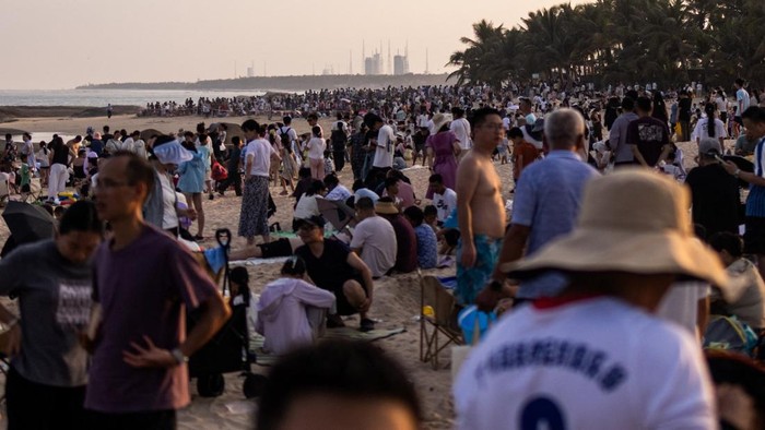 People gather at dusk at Qishui Bay Beach to watch the launch of a Long March 7A launch vehicle from the Wenchang Space Launch Site in Wenchang, Hainan province, China, August 10, 2026. On a sweltering August night, thousands on China's Hainan island thronged the beaches around the Wenchang Space Launch Site, phones raised, waiting for a show. Shortly after 8 p.m., the Long March 7A rocket blasted off. The crowd roared as its ascent lit up the night sky. Moments later, the uncrewed rocket turned into a ball of fire in midair, an unforeseen blast confirmed by Chinese state media a few hours afterwards. REUTERS/Maxim Shemetov            SEARCH 