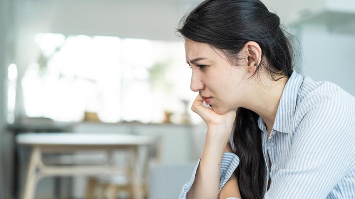 Asian beautiful unhappy woman sit on sofa feel frustrated and stressed. Attractive worried female having psychological problem feeling anxiety depression, upset and grief troubled for health at home.