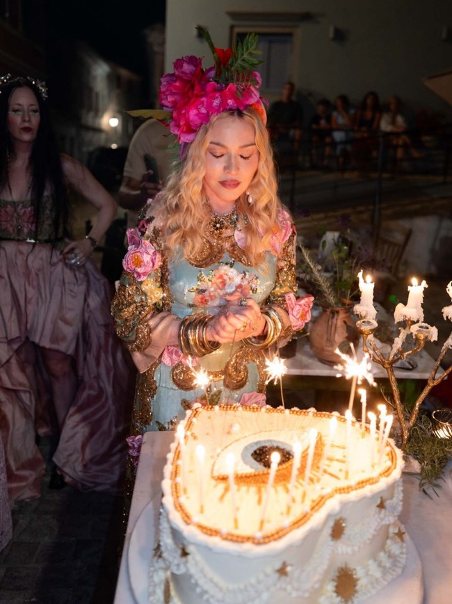 Gaun tampil dramatis dengan taburan payet dari atas hingga bawah, serta detail bunga yang dibuat dari kristal dan satin. Madonna kemudian melengkapinya dengan aksesori kepala yang dihiasi rangkaian mawar fuchsia berukuran besar. Foto: Instagram/@madonna