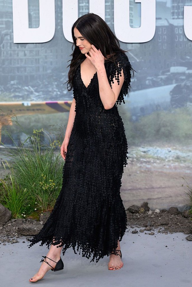 Ia memadukannya dengan gaun hitam berhiaskan fringe atau rumbai-rumbai bergaya bohemian. Gaun itu memiliki garis leher V yang cukup dalam serta detail cap sleeves. Foto: WireImage/Karwai Tang