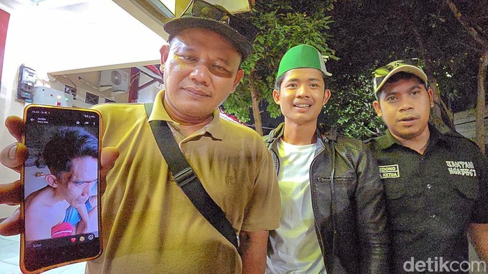 Roni memperlihatkan foto adiknya yang memar usai dianiaya oknum kades di Sukabumi