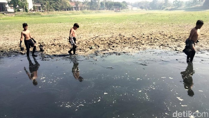 Anak-anak sedang bermain di waduk Desa Tenaru, Gresik yang mulai mengering