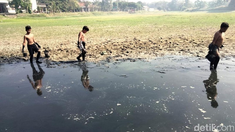 Anak-anak sedang bermain di waduk Desa Tenaru, Gresik yang mulai mengering