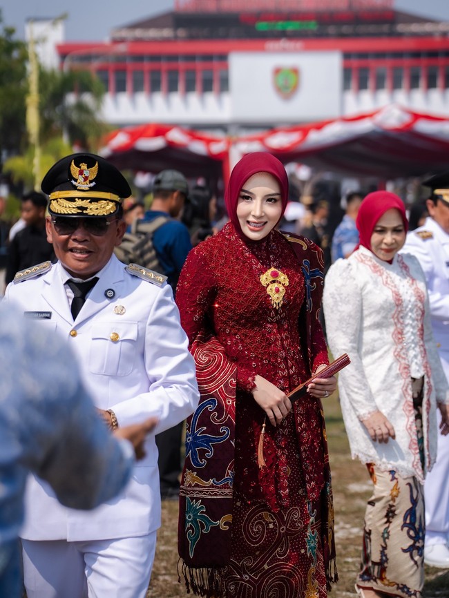 Kini penampilan Aisyah Thisia yang baru saja ulang tahun ke-27 itu juga jadi atensi. Saat mengikuti perayaan HUT RI ke-81, Thisia tampil dalam balutan kebaya kutubaru modifikasi berwarna merah marun dengan detail payet yang penuh dan mewah. Ia memadukannya dengan jilbab segi empat berwarna senada yang ditata rapi, serta kain batik lilit berwarna cokelat tua dengan motif floral berwarna cerah. Foto: Dok. Instagram @thisia.halijam.