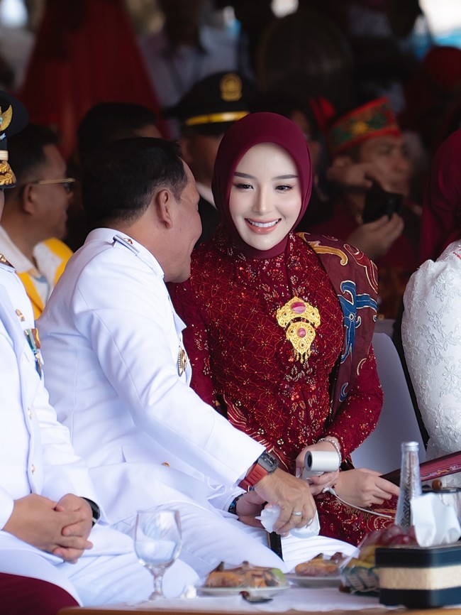 Gaya formal Thisia terlihat dari pilihan kebaya brokat panjang berwarna merah marun dengan aksen payet keemasan di bagian dada. Penampilannya disempurnakan dengan selempang kain batik panjang bermotif klasik yang anggun. Foto: Dok. Instagram @thisia.halijam.