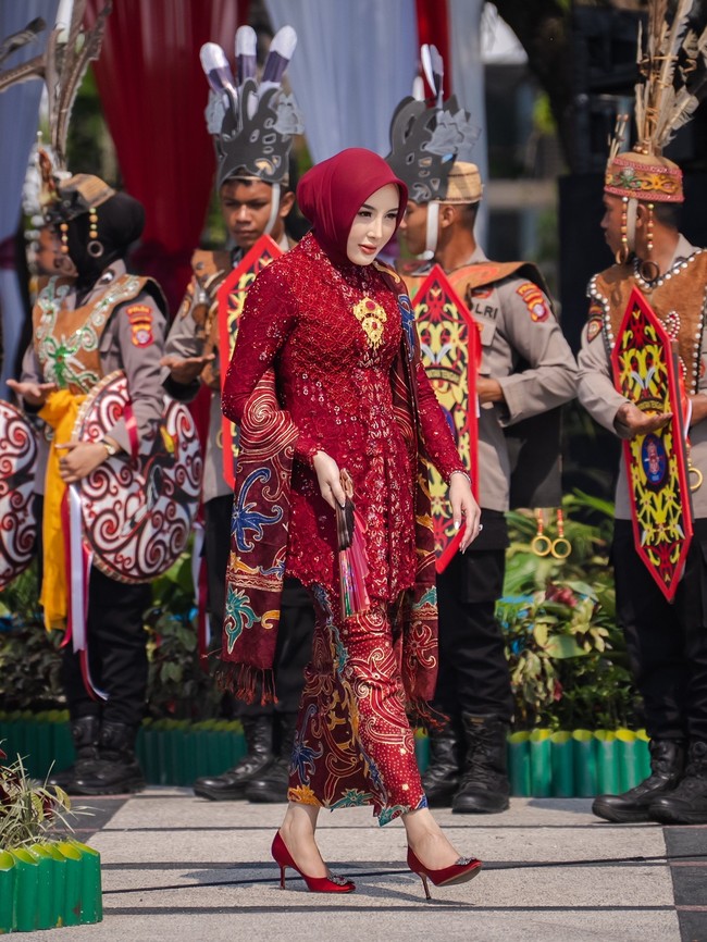 Aisyah Thisia memadukan kebaya brokat merah marun berpayet mewah dengan hijab segi empat warna senada yang ditata rapi. Penampilannya dilengkapi aksesori selendang batik berpola khas serta gelang emas. Foto: Dok. Instagram @hisia.halijam.