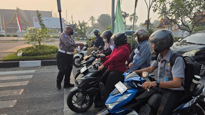 Kabut asap menyelimuti Kota Pekanbaru membuat jarak pandang menurun, Senin (24/8/2026). Ditlantas Polda Riau turun membagikan masker kepada pengendara.