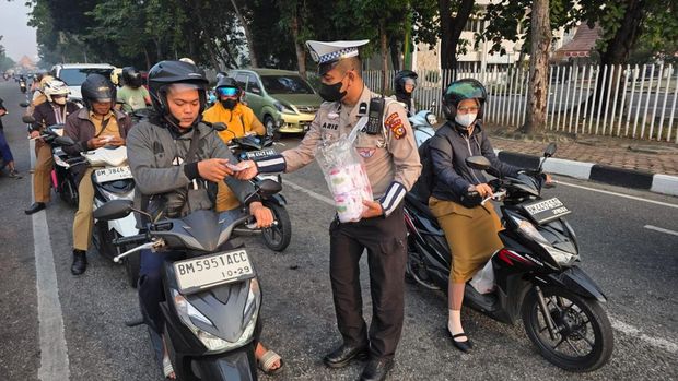 Kabut asap menyelimuti Kota Pekanbaru membuat jarak pandang menurun, Senin (24/8/2026). Ditlantas Polda Riau turun membagikan masker kepada pengendara.