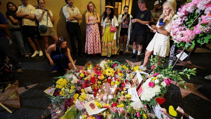 Dominique Nisperos and Lucy Sartor sing Dolly Parton songs at her star on the Hollywood Walk of Fame, as people gather near the star after it was announced that the country music icon died aged 80, in Los Angeles, California, U.S., August 25, 2026. REUTERS/Mario Anzuoni