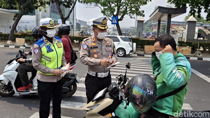 Polisi membagikan masker dan air minum kepada ojol di Palembang.