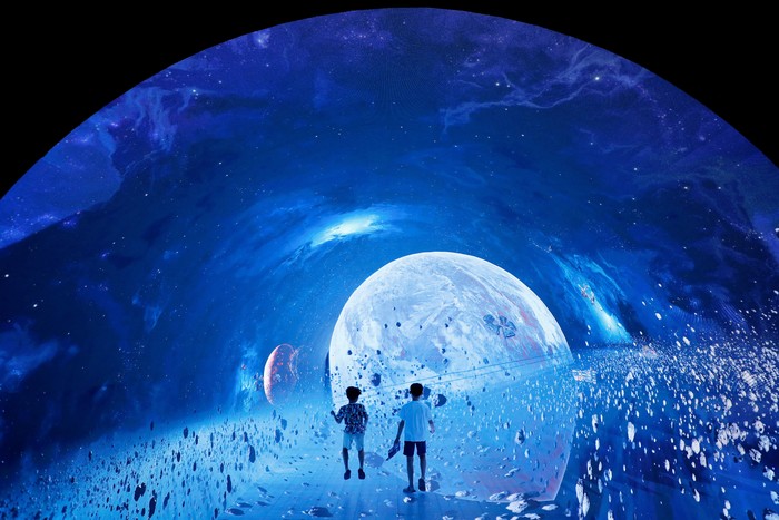 Boys play inside a space-themed immersive digital art installation 