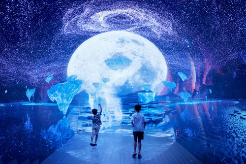 Boys play inside a space-themed immersive digital art installation 