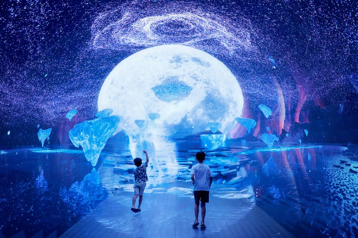 Boys play inside a space-themed immersive digital art installation 