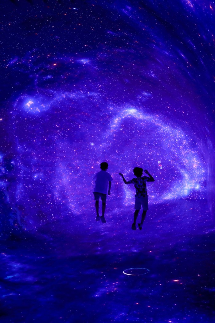 Boys play inside a space-themed immersive digital art installation 