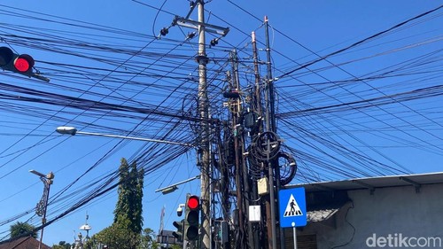 Tiang dan kabel provider terlihat semrawut di simpang empat Subagan atau patung kereta, Karangasem, Rabu (26/8/2026) (foto: I Wayan Selamat Juniasa)