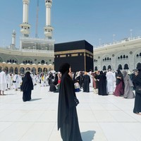 Ummi Quary tampil syari dengan balutan niqab berwarna hitam yang menutupi dada. Ia mengenakan abaya berwarna senada yang longgar dan santai saat berada di depan Kabah. Foto: Dok. Instagram @ummi_quary.