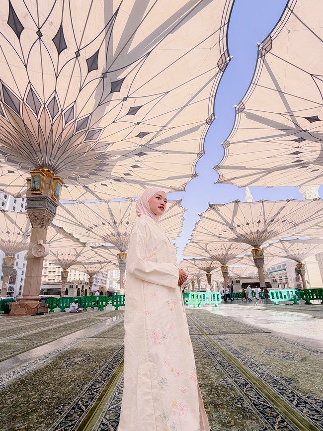 Ketika berada di halaman Masjid Nabawi, penampilannya menjadi sorotan saat memakai hijab pashmina instan simpel bernuansa pink soft yang membuat wajahnya terlihat cerah dan manis. Foto: Dok. Instagram @ummi_quary.