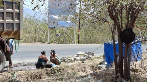 Pengungsi korban gempa mandi di pinggir Jalan Raya Trans Mbay-Ende, Kelurahan Lape, Kecamatan Aesesa, Nagekeo, NTT, Kamis (27/8/2026). Mereka mandi di sana karena tak ada fasilitas MCK. (Yufengki Bria/detikBali)
