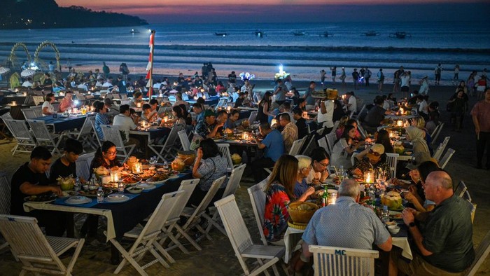 Wisatawan menyantap hidangan di Pantai Jimbaran, Badung, Bali, Rabu (26/8/2026). Dewan Nasional Kawasan Ekonomi Khusus (KEK) menargetkan devisa pariwisata Indonesia mencapai 39,4 miliar dolar AS pada 2029 atau setara Rp710,7 triliun, seiring upaya memperkuat peran sektor pariwisata dalam mendorong pertumbuhan ekonomi nasional melalui ekosistem investasi yang lebih kondusif dan berdaya saing. ANTARA FOTO/Fauzan/kye