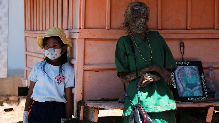 The exhumed remains of Toding and Ludia Ruruo stand in front of their burial chamber during Manene, a Torajan ritual where families exhume, clean and redress their deceased relatives to honour them, in Pangala, North Toraja, South Sulawesi province,