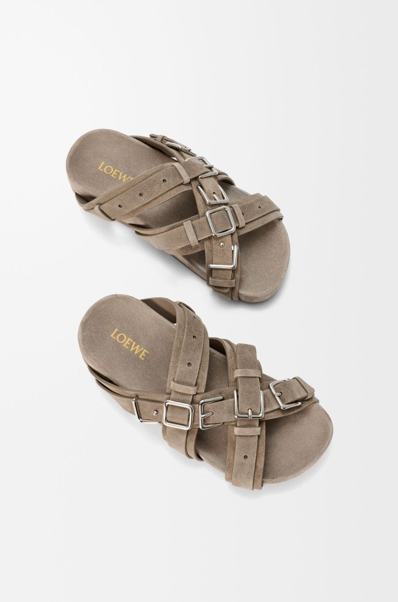 Sandal Loewe Viral Rumah mode asal Spanyol ini menghadirkan sandal yang menjadikan nama brand sebagai bagian dari desain melalui deretan buckle logam berukuran besar.