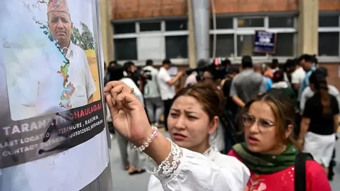 Dua perempuan memeriksa daftar orang hilang setelah banjir bandang di Nepal, di luar sebuah rumah sakit di Kathmandu, pada Jumat (28/08). (PRAKASH MATHEMA / AFP VIA GETTY IMAGES)