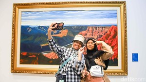 Pengunjung yang antusias berfoto di depan karya lukisan.