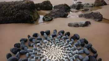Circuitus Meridiem, Jon Foreman. Jon Foreman menyusun batu-batu pantai menjadi pola melingkar seperti pancaran cahaya di Druidston, Wales, Inggris. Karya ini bersifat sementara dan dibuat langsung menggunakan material alami. Foto: Street Art Utopia