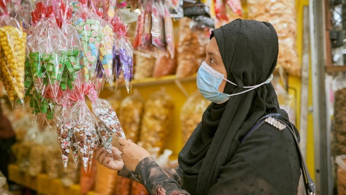 Muslim woman in hijab wearing face mask shopping at a popular kerepek snack shop in Ayer Hitam, Johor, Malaysia