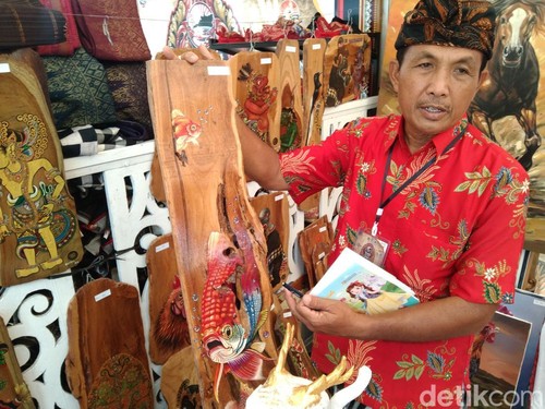 I Wayan Sution Ariawanmenunjukkan karya lukisdengan media limbah kayu. (Foto:Krisna Pradipta/detikBali)