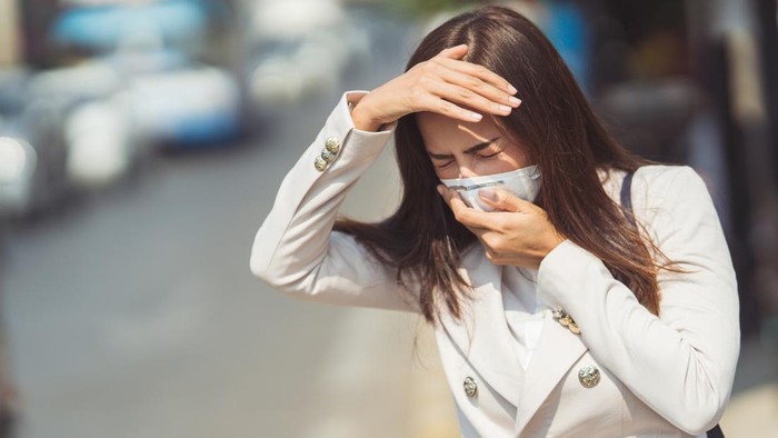 Asian woman are going to work.she wears N95 mask.prevent PM2.5 dust and smog.she is coughing