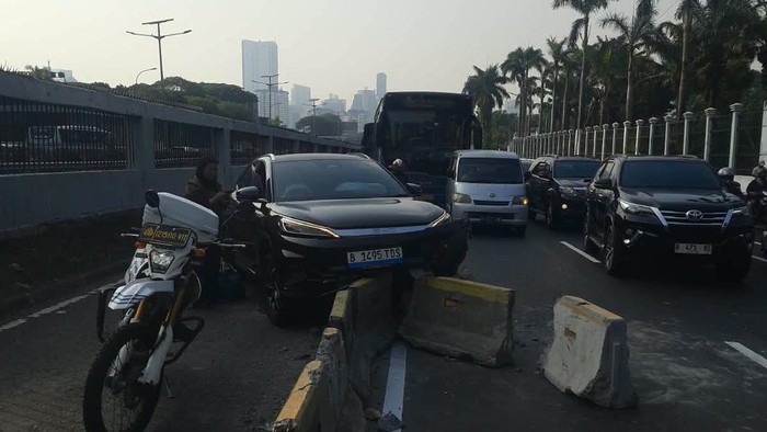 Mobil listrik menabrak motor dan separator busway dekat DPR Jalan Gatot Subroto arah Slipi, Senin (31/8/2026).